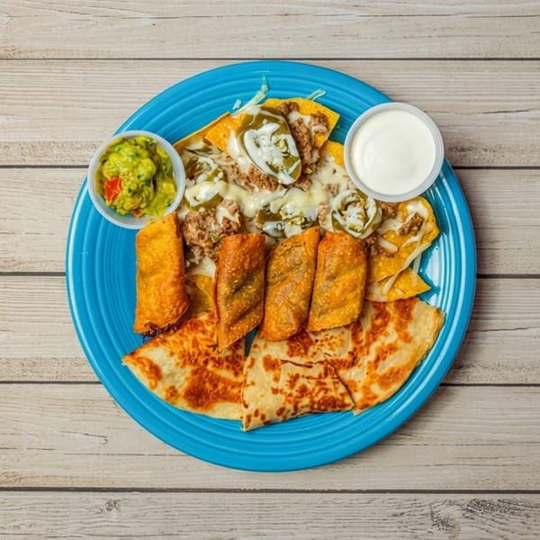 Blue plate with nachos, taquitos, quesadillas, guacamole, and sour cream on a wooden table.